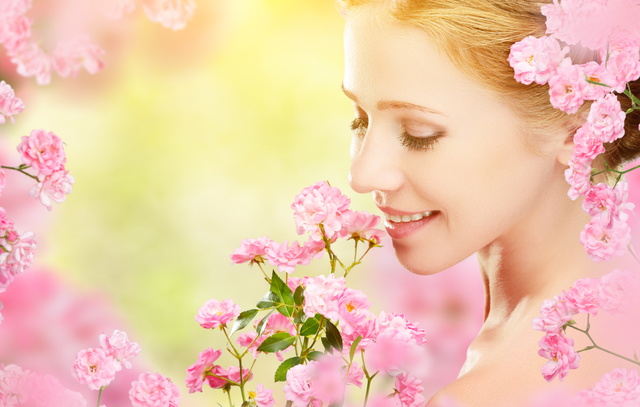 Beauty face of young beautiful woman with pink flowers in her hair